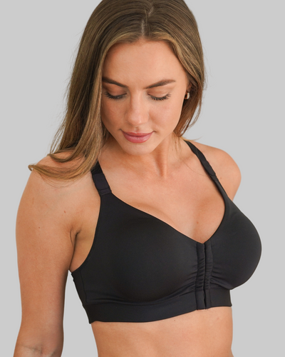 Woman wearing a black nonlace surgical bra/sports bra against a gray background